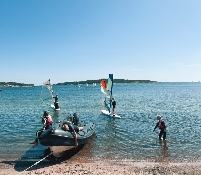 Kids by the beach with windsurfers and a rescue boat at Sandhamn