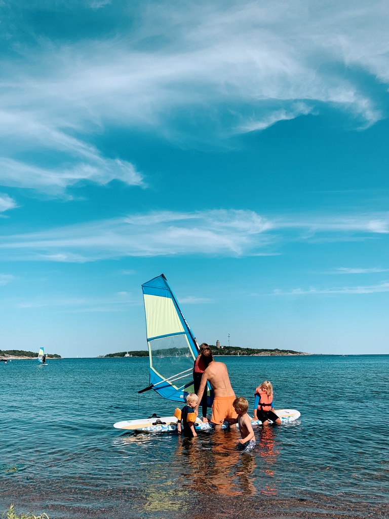 Instructor rigging a windsurf sail with kids in the water